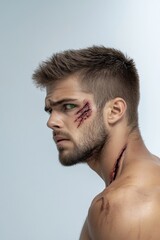 Obraz premium Adult man with medium skin and stubble has theatrical wounds and green eyes looking to the side, against a plain background
