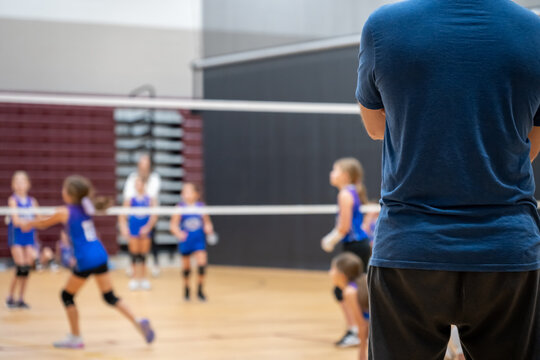 Selective focus behind a coach at a youth volleyball match, blurred game.  - Powered by Adobe