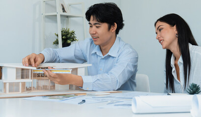 Portrait of cooperative engineer team working together to measure house model by using ruler and...