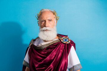 Photo of handsome senior male look camera serious face wear ancient greek god king dress isolated on blue color background