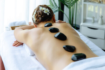 Hot stone massage at spa salon in luxury resort with day light serenity ambient, blissful woman...