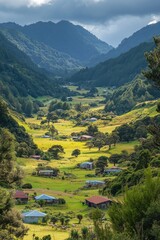 Mountain valley landscape. Houses in a green field. Lush trees and hills under a cloudy sky. Peaceful scenic view.
