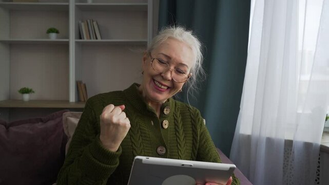 Elderly woman celebrating a personal achievement with a tablet