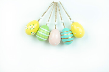 Five pastel Easter eggs with delicate painted patterns, hanging from twine against a white background. A festive composition perfect for holiday decorations, greeting cards, and seasonal projects.