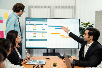 Project manager planning schedules for business task at meeting room, Gantt chart software show on TV screen. Multi ethnic diversity business people and modern business project management. Habiliment