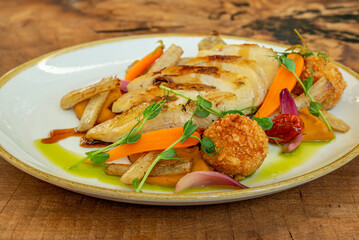 Gourmet plated roasted chicken with vegetables and croquette
