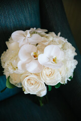 Elegant white floral bouquet featuring orchids and roses arranged beautifully on a chair