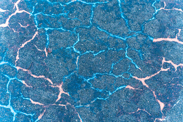 The rock has a blue and pink color with cracks in it. The cracks are blue and pink, and they are scattered all over the rock. The rock appears to be old and worn, with the cracks giving it a unique