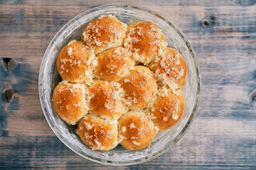 Dish with ruddy donuts is on a wooden table. Top view
