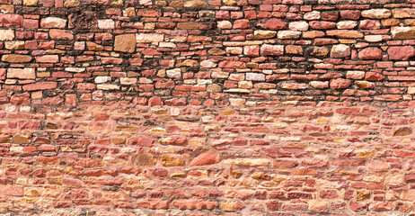 Naklejka premium Ancient red stone wall showing different construction phases. Abstract background
