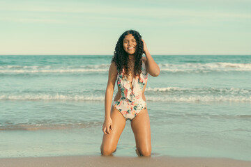Young woman kneeling on the beach enjoying summer vacations