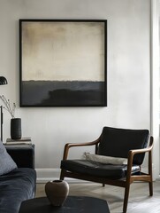 A square painting hangs above a black leather armchair