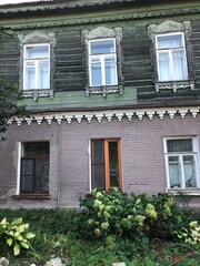 Wall of an old brick and wooden  house and a flower bed under the windows. House in a Russian village. Kolomna, Russia.