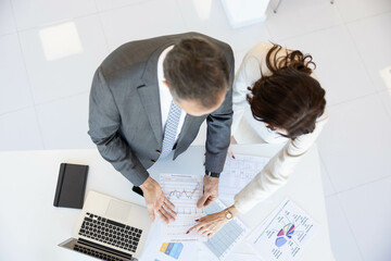 Two professionals collaborate over detailed data visualizations and graphs on their workspace, exemplifying teamwork and strategy.