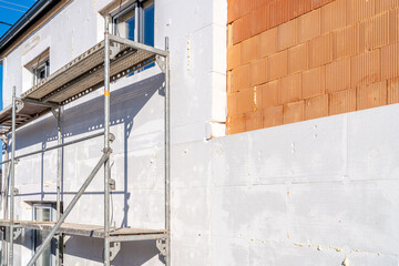 Workers installing external thermal insulation with scaffolding on residential building