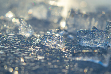 Fototapeta premium Beautiful transparent different pieces of ice on the ice surface. Pieces of ice filled with bubbles, a solid background. dishes, frozen water is clean. High quality photo