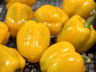  Vibrant yellow peppers are abundant in a market basket, showcasing their freshness and vivid color. Close-up