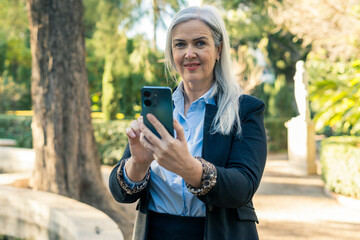 Businesswoman using smartphone in a park during a sunny day