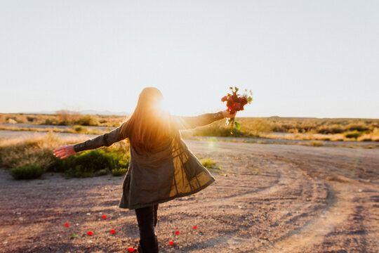 Woman walking in sunlight with roses