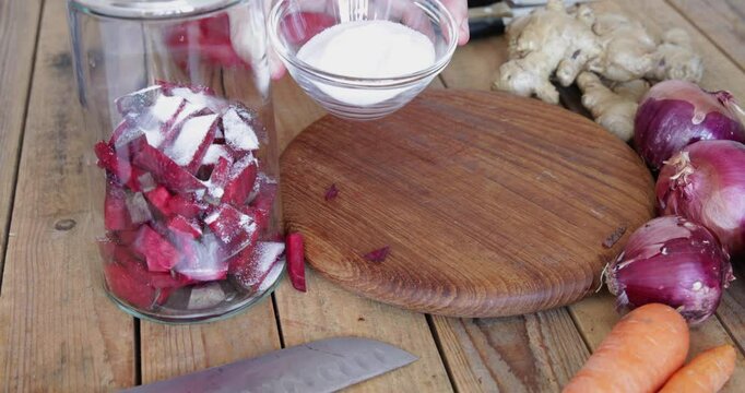 Red beet root naturally fermented kvass preparing, adding salt into glass jar with beetroot slices