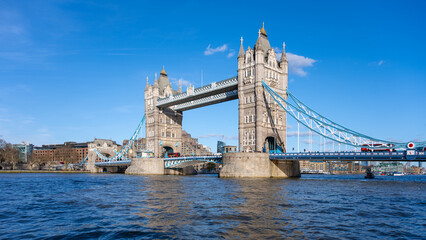 Tower Bridge stands majestically against a clear blue sky in London. The sunlight highlights its...