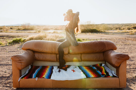 Woman with bouquet of flowers on back of couch in desert