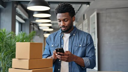 Efficient man using phone in modern indoor workspace surrounded by stacked boxes - Powered by Adobe