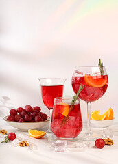 Glasses of grape cocktail, red wine and juice with grapes, ice and citrus slices on sunny background, bar and summer party concept, restaurant and cafe advertising card, selective focus.