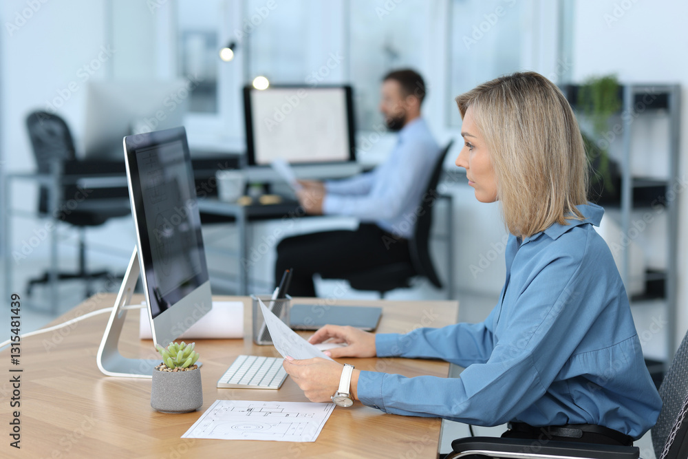 Poster technician making digital engineering drawing on computer at desk in office