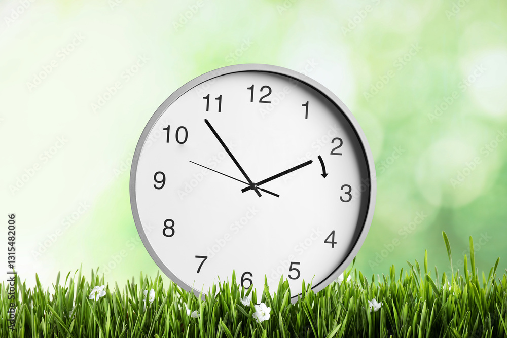 Poster Clock in green grass with flowers. Arrow showing time change one hour ahead in spring. Daylight saving time