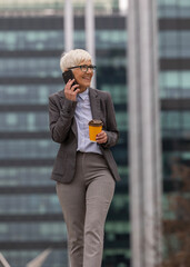 Businesswoman walking in urban environment and talking on phone
