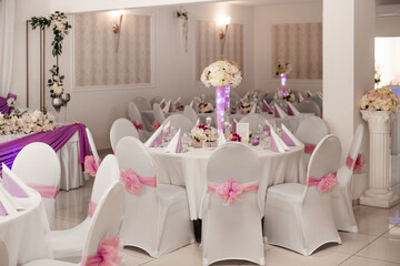 A wedding table setup with white chairs and soft purple details, ready for guests.