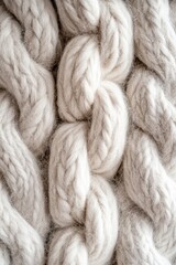 Close-up view of thick, textured white knit fabric showcasing intricate braided patterns, ideal for textile design inspiration