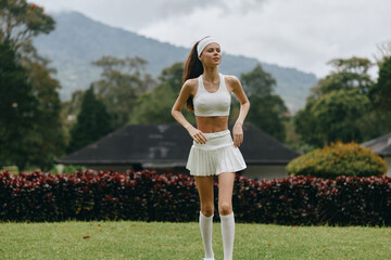 Young athletic woman jogging in a white sports outfit, showcasing determination and fitness against...