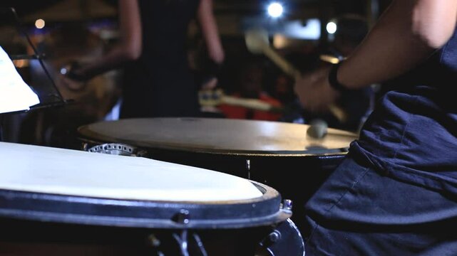 orchestra musician playing timpani with drumsticks at night concert