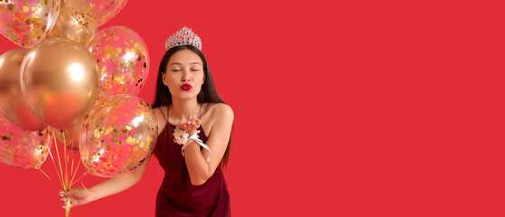 Beautiful Asian prom queen with balloons blowing kiss on red background © Pixel-Shot
