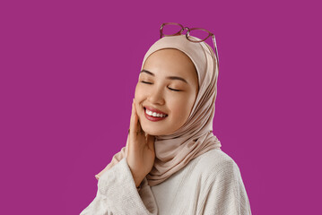 Young Muslim woman on purple background