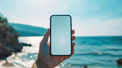 Hand holding smartphone by sea with mountain view, Mockup