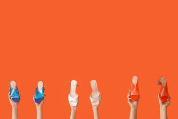 Women with stylish shoes on orange background