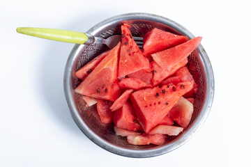 Freshly cut watermelon slices in a metal bowl with a fork on a white background, Top view