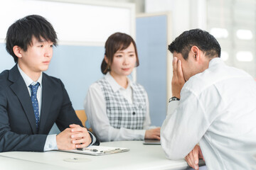 窓口で落ち込む顧客の相談に乗るビジネスマン（困る・ショック・借金・倒産・自己破産）
