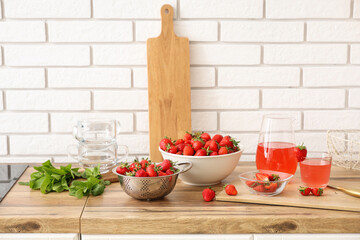 Bowl with tasty strawberries and juice on counter in kitchen