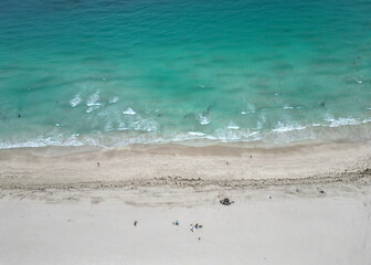 Beach vacation at sea in summer. Sea relax under the sun. Travel to sea. Aerial top view of sand beach with crystal clear turquoise water. Enjoying beach sun. Summer vacation in paradise