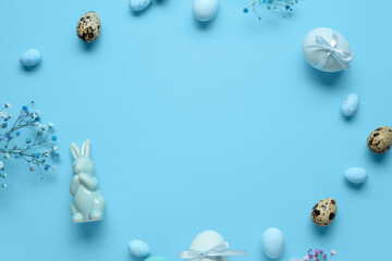 Frame made of decorative bunny, flowers and Easter eggs on blue background