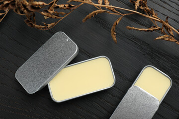 Natural solid perfume and dry branch on black wooden table, flat lay