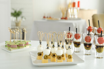 Many different tasty canapes on white table indoors