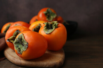Delicious fresh juicy persimmons on wooden table, closeup. Space for text
