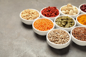 Different superfoods in bowls on grey table, closeup. Space for text