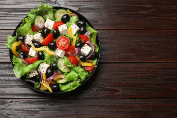 Delicious fresh Greek salad on wooden table, top view. Space for text
