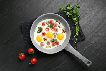 Tasty fried eggs with cut sausages and mushrooms served on black table, flat lay